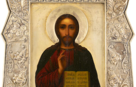 Dieses Bild zeigt eine ikonografische Darstellung von Jesus Christus, gemalt in traditioneller russischer Art. Jesus ist in einem dunkelroten Gewand gekleidet, verziert mit einem goldenen Nimbus um seinen Kopf. Er hält seine rechte Hand in einem Segensgestus und in seiner linken Hand ein geöffnetes Buch mit kyrillischer Schrift.