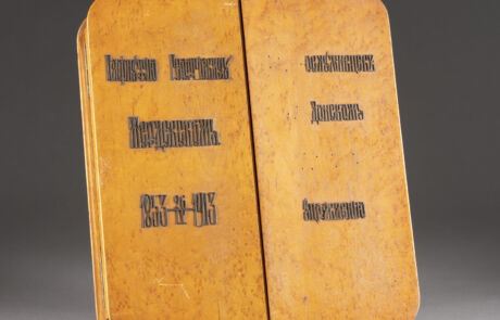 Bild eines antiken, gelb-orangefarbenen Buchs geöffnet auf einer Doppelseite, wobei jeder Deckel sichtbar ist. Die russische kyrillische Schrift auf beiden Seiten des Buchs deutet auf eine historische Bedeutung oder Herkunft hin. Der allgemeine Zustand zeigt leichte Alters- und Gebrauchsspuren.