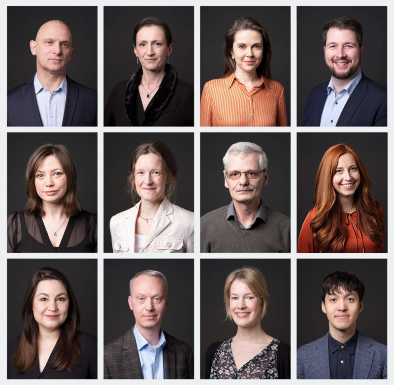 Collage von zwölf Porträtfotos, jeweils in drei Reihen zu vier Bildern angeordnet, mit verschiedenen Männern und Frauen vor einem dunklen Hintergrund. Jede Person trägt Geschäftskleidung und blickt direkt in die Kamera.