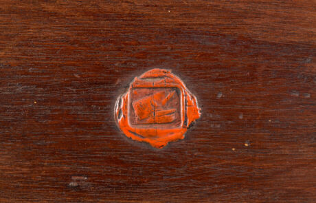 Nahaufnahme eines antiken roten Wachssiegels auf einem Holzuntergrund, historisches Sammlerstück bei einer Kunstauktion.