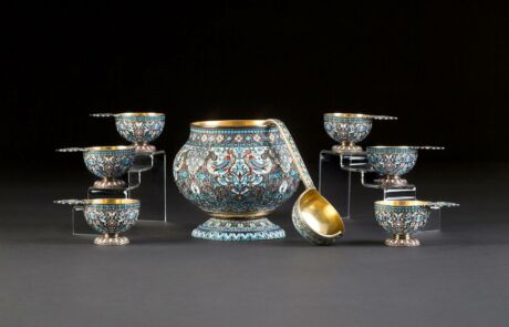 Close-up of an elaborately decorated object, presumably a vase, from an auction house. The decoration features intense blue, red, and green colors with floral and geometric patterns framed by golden lines. It impresses with its detailed ornamentation and precise craftsmanship.