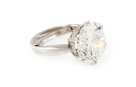 Ein großer, glitzernder Diamantring mit einem auffälligen Mehrkaräter in einer klassischen Krappenfassung, der den Stein prominent hervorhebt. Der Ring ist aus glänzendem Silber oder Weißgold gefertigt und auf einem weißen Hintergrund fotografiert, was den Kontrast und die Brillanz des Diamanten betont.