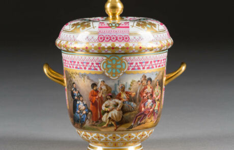 Detailreich verzierter antiker Porzellanpokal mit farbenfrohen historischen Szenen und Goldakzenten, ausgestellt bei einer Kunstauktion.