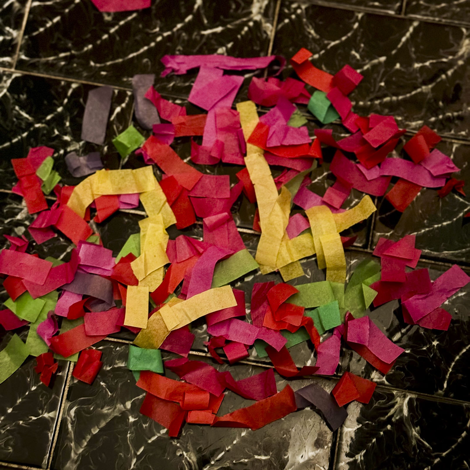 Bunte Konfettistücke aus Papier auf schwarz marmoriertem Hintergrund, arrangiert zu einer lockeren Form der Zahlen 2024 zur Feier des Neujahrs.