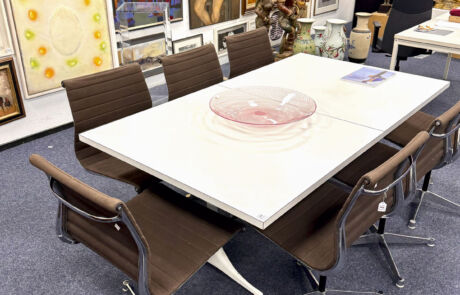 Moderne Kunstinstallation auf einem Konferenztisch bei einer Kunstauktion, umgeben von Stühlen.