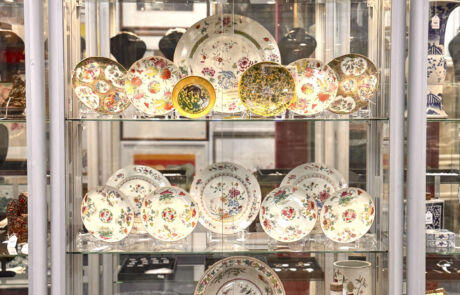 Regal mit verschiedenen bemalten, antiken Porzellantellern bei einer Kunstauktion.