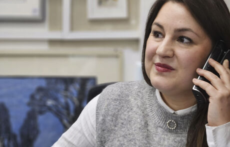 Frau im Büro telefoniert, im Hintergrund sichtbares Gemälde.