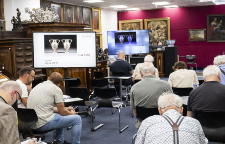 Blick in einen Auktionssaal bei Hargesheimer, Besucher beobachten eine Präsentation historischer Kunstwerke.